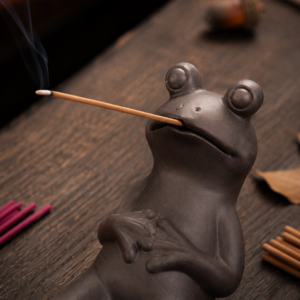 Incensário em argila roxa com sapo relaxando segurando incenso de vareta.