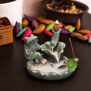 Incensário cascata decorativo de cerâmica com sapo e folhas de lótus criando efeito visual de fumaça descendente.