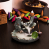 Incensário cascata decorativo de cerâmica com sapo e folhas de lótus criando efeito visual de fumaça descendente.