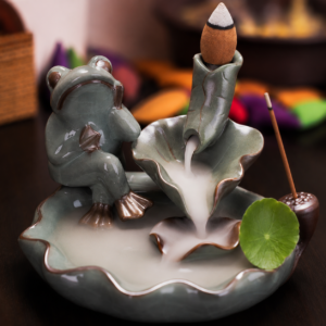 Incensário cascata decorativo de cerâmica com sapo e folhas de lótus criando efeito visual de fumaça descendente.